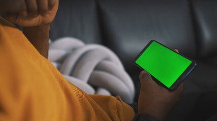 Close up smartphone with green screen in the hands of unrecognizable african american black man. High quality photo
