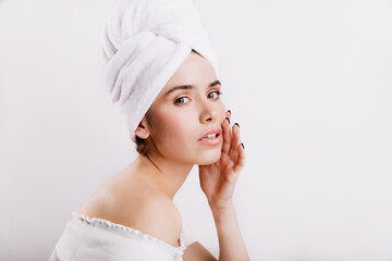 Closeup portrait of model in towel on head. Girl without make-up gently touches her face