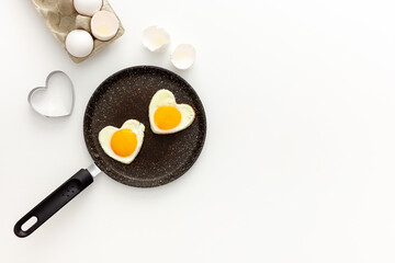 Cooking heart-shaped fried eggs in a pan