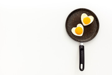 Cooking heart-shaped fried eggs in a pan
