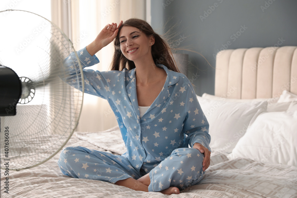 Sticker woman enjoying air flow from fan on bed in room. summer heat