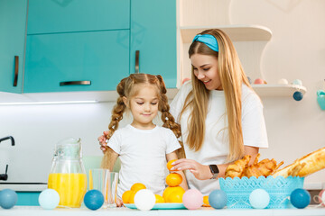 Obraz na płótnie Canvas Happy young mother baking croissant for her daughter in the kitchen at home. Happy family relationships
