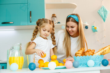 Obraz na płótnie Canvas Happy young mother baking croissant for her daughter in the kitchen at home. Happy family relationships