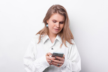 Photo of young woman in white shirt using smartphone over white background.
