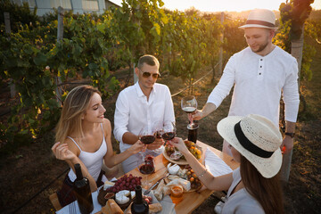 Friends holding glasses of wine and having fun in vineyard