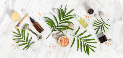 Natural SPA cosmetic products background, Composition with bottles of essential oils, sea salt and massage rollers on white marble background