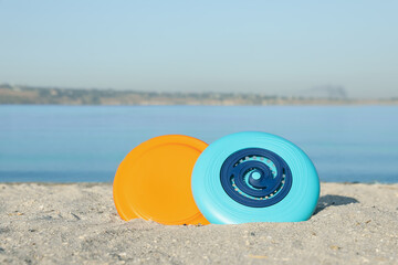 Plastic frisbee discs on sandy beach near river