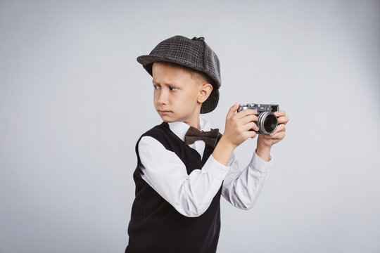 Cute little detective with vintage camera on grey background