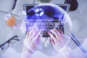 Double exposure of man's hands typing over laptop keyboard and forex chart hologram drawing. Top view. Financial markets concept.