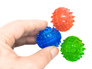 A hand picks up a blue massage ball from a pile of su jok therapy balls. Close-up movement is isolated on a white background. Development of fine muscles of the hand and motor skills of the fingers.