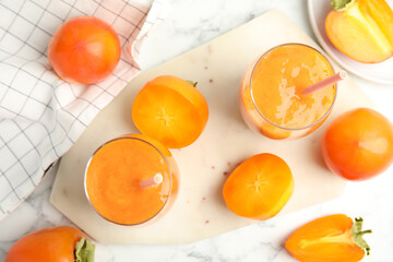 Tasty persimmon smoothie with straws and fresh fruits on white marble table, flat lay
