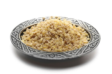 Dry bulgur pile in oriental engraved and decorated metal bowl isolated on white background