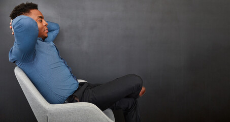Business Mann sitzt entspannt vor einer Wand