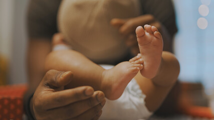 Close up, baby feet. African american man playing with little feet of his baby. High quality photo