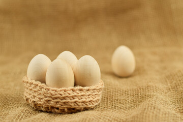 Decorative wooden Easter eggs in a wicker basket. Eastern eggs closeup on a vintage background.