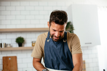 Portrait of handsome man in kitchen. Young man preparing delicious food.