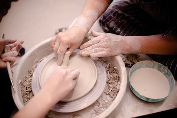 Female hands crafting a pottery cup on a potter's wheel. Handmade and crafting concept.