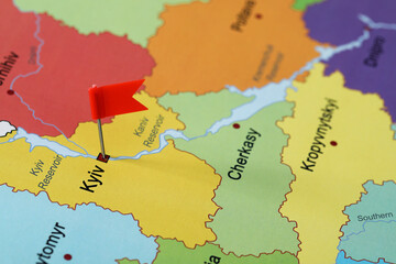 Map of Ukraine with red flag push pin placed on Kyiv, closeup