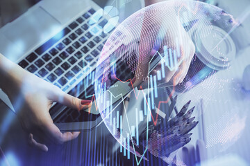 Double exposure of businesswoman hands typing on computer and financial graph hologram drawing. Stock market analysis concept.