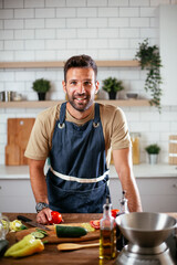 Portrait of handsome man in kitchen. Young man preparing delicious food.
