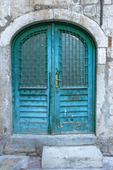 Fototapeta na wymiar Beautiful vintage blue painted door. Blue grunge wooden door in brick wall. Old rustic wooden doors in Montenegro, Europe