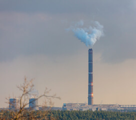 Fototapeta na wymiar Smoke from chimneys at the plant in the rays of the sunset as a background.