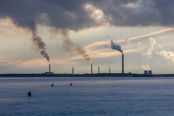 Obraz premium Smoke from chimneys at a factory near a frozen lake