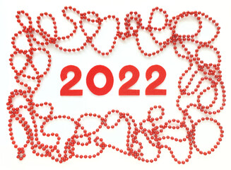 Red felt numbers 2022 on white background. Red beads around. Flat lay for Valentine's Day or New Year.