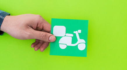 Female hand holding delivery motorcycle shape symbol, on red background.