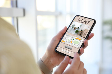 Woman searching for apartment on rental property website via smartphone, closeup