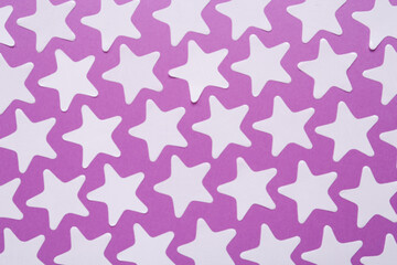 White star shaped confetti on violet background, flat lay