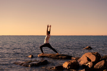 Attractive young man practicing yoga meditation and breathwork outdoors by the sea