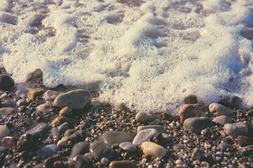 Waves washing over gravel beach, macro shot.