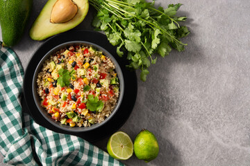 Mexican salad with quinoa in bowl on gray stone. Top view. Copy space