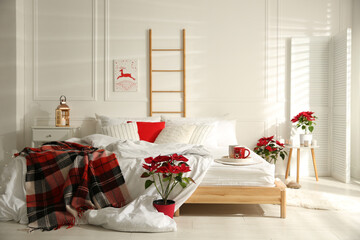 Christmas bedroom interior with red woolen blanket and poinsettias