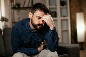 Sick man at home. Young man sitting on sofa having fever