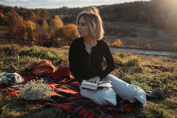 Young cheerful student girl with bouquet of camomiles and book. gen z