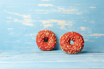 Two red donuts on rustic blue wooden background