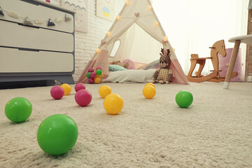 Bright toy balls near play tent on floor in child's room © New Africa