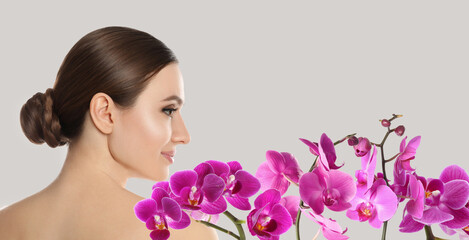 Fototapeta premium Beautiful young woman and orchid flowers on light background, banner design. Spa portrait