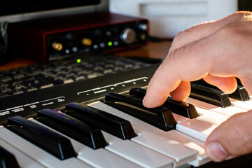 Fototapeta na wymiar Music producer working with a midi keyboard and a computer..