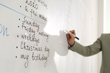 English teacher giving lesson in classroom, closeup. Focus on whiteboard