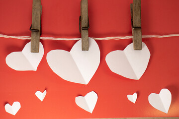 white valentines hanging on a rope with clothespins on a red background