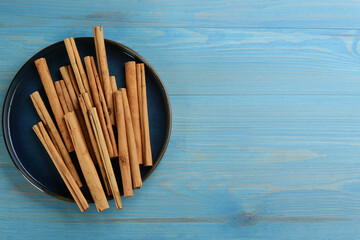Aromatic cinnamon sticks on light blue wooden table, top view. Space for text