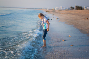Little girl playing with sand on the beach. A cheerful child. The concept of summer vacation.