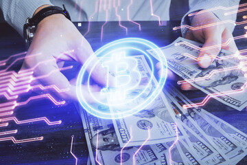 Multi exposure of blockchain theme drawing hologram and USA dollars bills and man hands. Business concept.