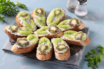 Homemade sandwiches with kiwi, cream cheese and garlic on a plate on light blue background. Closeup