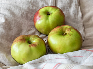 Three green apples lie on different fabrics