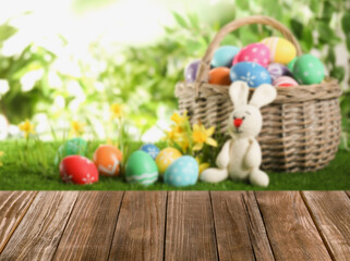 Fototapeta na wymiar Empty wooden surface and wicker basket with colorful Easter eggs on background