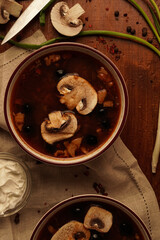 Flat-lay of mushroom soup with sour cream and onion on wooden table
